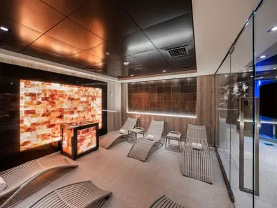 Ein moderner Salz-Entspannungsraum mit beleuchteten Salzwänden und mehreren Liegen im MSC Aurea Spa an Bord der MSC Euribia.