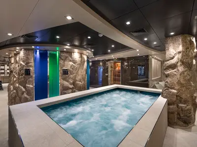 Im Thermalbereich der MSC Euribia ist ein sprudelnder Whirlpool zu sehen. Felswände und farbige Lichtsäulen schaffen ein modernes und entspannendes Spa-Ambiente.