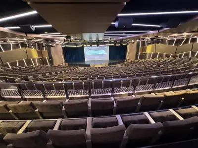 Blick von den oberen Sitzreihen auf die Bühne im großen, eleganten Theater an Bord der MSC Euribia.