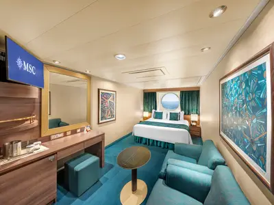 Helle, modern eingerichtete Aussenkabine an Bord der MSC Fantasia. Doppelbett, Bullauge mit Meerblick, TV-Bereich, Schreibtisch und Sitzgelegenheit in Türkistönen.