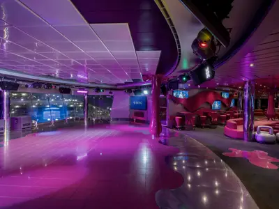 Die Liquid Disco an Bord der MSC Fantasia bei Nacht, beleuchtet in leuchtendem Lila, mit glänzender Tanzfläche, Sitzbereichen und Bildschirmen.