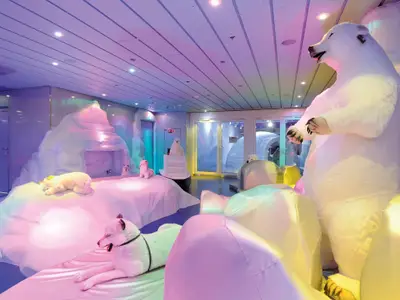 Der farbenfroh beleuchtete Kinderbereich Il Polo Nord an Bord der MSC Fantasia. Pluesch-Eisbaeren, Robben und eine künstliche Eislandschaft erzeugen eine arktische Spielwelt.