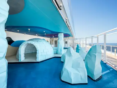 Kinderbereich "Polo Nord" an Bord der MSC Fantasia: blaues Iglu, Eisberg-Skulpturen, blauer Boden. Überdacht, mit Meerblick unter klarem Himmel.