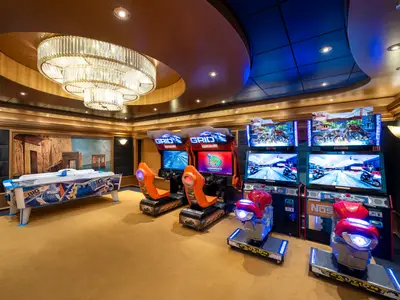 Ein moderner Arcade-Spielebereich an Bord der MSC Fantasia mit Rennsimulatoren und Airhockey. Die Einrichtung ist luxuriös mit einem großen Leuchter.