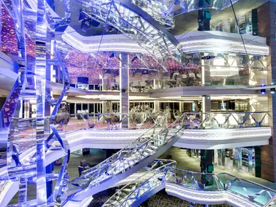 Das mehrstöckige, elegant gestaltete Infinity Atrium an Bord der MSC Grandiosa mit futuristischer blauer Lichtinstallation, glänzenden Oberflächen und einer geschwungenen Treppe.