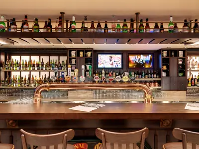 Die Masters of the Sea Bar an Bord der MSC Grandiosa zeigt eine Kupfer-Zapfanlage, Bierflaschen, Bildschirme und eine Holztheke mit Gläsern.