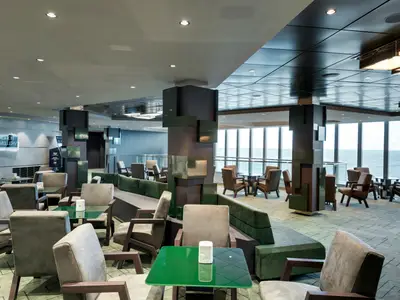 Geräumige Edge Cocktail Bar an Bord der MSC Grandiosa mit modernen Sitzbereichen, Tischen und großen Fenstern, die den Blick auf das weite Meer freigeben.