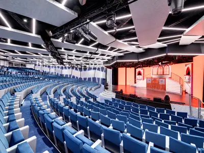 Das moderne Theater La Comédie an Bord der MSC Grandiosa mit blauen Sitzen, einem großen Bühnenbereich mit aufwendigem Set und stylischer Deckenbeleuchtung. Der Raum ist leer.