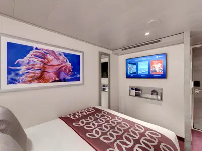 Moderne Innenkabine an Bord der MSC Grandiosa. Zu sehen sind ein Einzelbett mit gemusterter Tagesdecke, ein großes Kunstwerk einer rosa Seeanemone und ein Flachbildfernseher mit Bordinformationen.