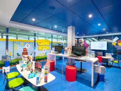 Detailaufnahme des Doremilab-Spielezimmers an Bord der MSC Grandiosa, ausgestattet mit Computern, Spieltischen und interaktiven Wänden im Videospiel-Design. Der Raum ist kinderfreundlich und modern gestaltet.