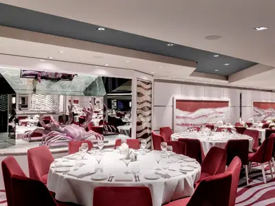 Blick in das stilvolle Hauptrestaurant "Purple Crab" an Bord der MSC Grandiosa mit festlich gedeckten Tischen, roten Samtstühlen und einer markanten lilafarbenen Krabbenskulptur im Vordergrund.