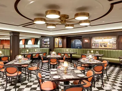 Grosszügiges L'Atelier Bistrot Restaurant an Bord der MSC Grandiosa mit grünen Bänken, orangefarbenen Stühlen, Holzelementen, Kunstwerken und Schachbrettmuster-Boden.