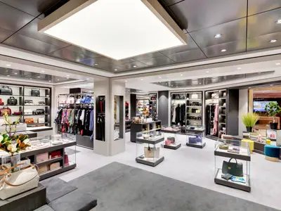 Ein geräumiger, modern eingerichteter Shop an Bord der MSC Grandiosa mit Auslagen von Designertaschen, Kleidung und Accessoires auf Regalen und in Vitrinen.