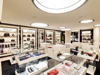 Eleganter Luxus-Shop an Bord der MSC Grandiosa. Handtaschen, Schuhe und Accessoires von Bally und Michael Kors in Vitrinen und Regalen. Heller, moderner Raum.