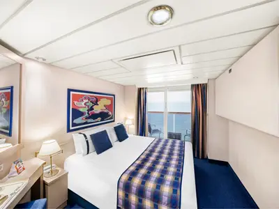 Helle Balkonkabine an Bord der MSC Lirica mit bequemen Doppelbett, farbenfrohem Kunstwerk, Schreibtisch und Meerblick vom privaten Balkon.