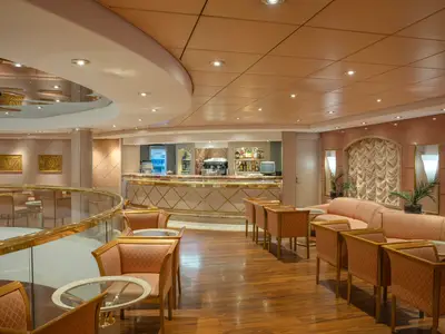 Eleganter Bar- und Loungebereich auf der MSC Lirica. Komfortable Sessel und Sofas, Holzboden und eine geschwungene Bar. Warme Beleuchtung schafft einladende Atmosphäre.