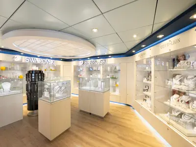Eine helle und moderne Schmuckboutique an Bord der MSC Lirica. Glasvitrinen zeigen funkelnde Halsketten und Accessoires von Marken wie Swarovski und Coeur de Lion. Die Boutique hat eine elegante Holzausstattung und punktuelle Beleuchtung.