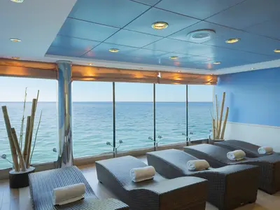 Ruhebereich im MSC Aurea Spa der MSC Lirica. Liegen mit Handtüchern vor Panoramafenstern bieten Blick auf das Meer und den Himmel. Bambus-Dekorationen.