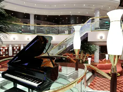 Glänzendes Grand Piano im eleganten Atrium der MSC Magnifica. Luxuriöse Lounge-Bereiche und eine prunkvolle Treppe mit goldenen Akzenten prägen das stilvolle Ambiente.