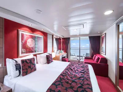 Helle, moderne Balkonkabine an Bord der MSC Magnifica. Ein grosses Bett, ein Sofa und ein Schreibtisch sind zu sehen, mit Zugang zum Balkon und Meerblick.