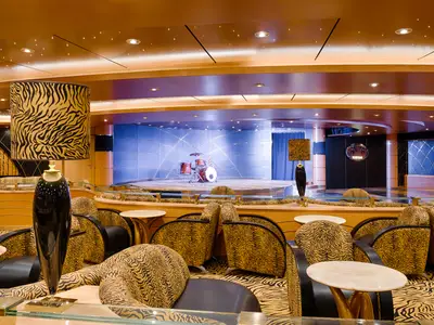 Die Tiger Bar auf der MSC Magnifica. Tigerfellmuster auf Möbeln und Lampen. Bühne mit Schlagzeug. Warme Beleuchtung.