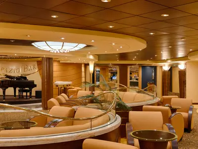 Die elegante Topazio Bar an Bord der MSC Magnifica. Ein Flügel steht auf der Bühne, umgeben von goldbraunen Sofas und Sesseln. Warme Beleuchtung und glänzende Balustraden schaffen ein luxuriöses Ambiente.