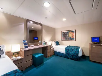 Geräumige, barrierefreie Innenkabine an Bord der MSC Magnifica mit zwei Einzelbetten und einem Schreibtischbereich. Ein TV und ein Minikühlschrank sind integriert. Blauer Teppichboden.