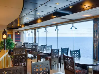 Das orientalisch gestaltete Sahara Buffet an Bord der MSC Magnifica bietet Tische und Stühle sowie einen weiten Meerblick durch Panoramafenster.