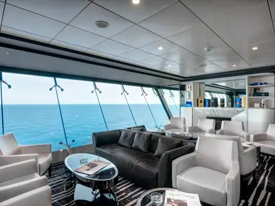Die elegante Smoking Room Lounge an Bord der MSC Meraviglia bietet bequeme Sessel und Sofas mit weitem Blick auf das Meer durch große Panoramafenster.