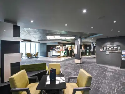 Ein Blick in die moderne Edge Cocktail Bar an Bord der MSC Meraviglia. Gäste sitzen an der hell beleuchteten Bar und an Tischen. Der Innenraum hat stilvolle Möbel und große Fenster.