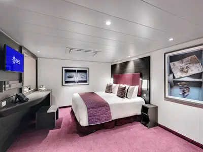 Geräumige barrierefreie Kabine der MSC Meraviglia: Doppelbett, Schreibtisch, TV und maritime Wandkunst. Moderner Stil mit violettem Teppich.