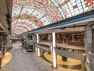 Blick in die moderne Galleria Meraviglia an Bord der MSC Meraviglia. Eine weitläufige Promenade mit LED-Kuppeldach im Buntglas-Design und Geschäften auf mehreren Ebenen.