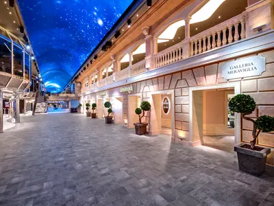 Lange Promenade Galleria Meraviglia an Bord der MSC Meraviglia. Die gewölbte LED-Decke simuliert einen Sternenhimmel. Entlang der Promenade reihen sich Geschäfte in modernem und klassischem Stil.