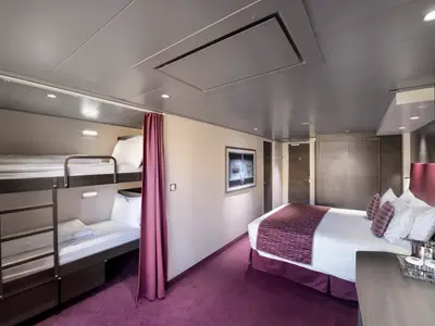 Eine modern eingerichtete Familienkabine an Bord der MSC Meraviglia mit einem Doppelbett, zwei Etagenbetten und lila Teppichboden. Ein Vorhang trennt den Bereich mit den Etagenbetten ab.