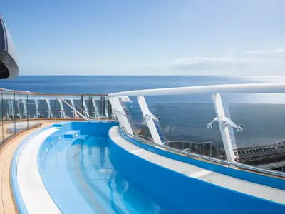 Auf dem Sonnendeck der MSC Meraviglia: Ein hellblauer Whirlpool mit Meerblick. Im Hintergrund das weite, blaue Meer unter klarem Himmel, durch eine Glasbalustrade getrennt.