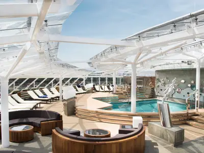 Exklusiver Poolbereich an Bord der MSC Meraviglia: blauer Pool, Holzdecks, Liegestühle, moderne Glasüberdachung. Fisch-Skulpturen an einer Wand.