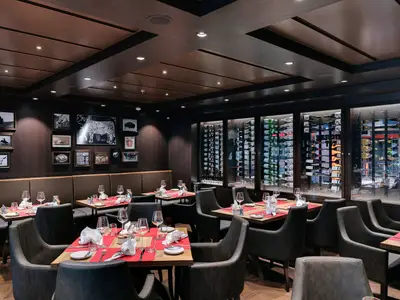 Das elegante Spezialitätenrestaurant Butcher's Cut an Bord der MSC Meraviglia. Gedeckte Tische, Lederstühle und eine beleuchtete Weinwand prägen das gehobene Ambiente.