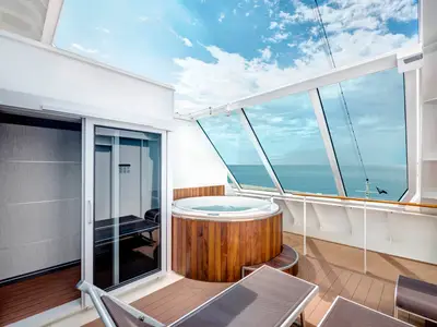 Eine geräumige MSC Yacht Club Duplex Suite der MSC Meraviglia mit privatem Deck, Whirlpool und grossen Glasfenstern zum Meer. Ein Schiebefenster führt ins Innere.
