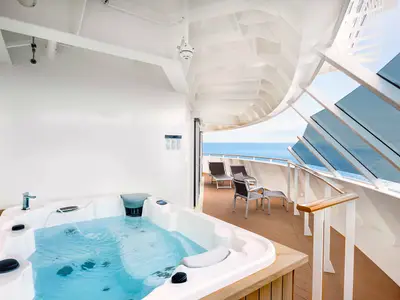 Eine luxuriöse Grand Suite Aurea der MSC Meraviglia mit privatem Whirlpool, Liegestühlen und einer Terrasse mit weitem Meerblick.