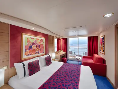 Helle Balkonkabine der MSC Musica mit Doppelbett, rotem Sofa und Schreibtisch. Der Balkon bietet einen weiten Meerblick. Modern und einladend gestaltet mit farbigen Akzenten.