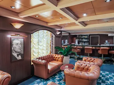 Elegante Bar-Lounge an Bord der MSC Musica mit dunkler Holzvertäfelung, cognacfarbenen Chesterfieldsesseln und Marmorbar. Ein markantes Gemälde ziert die Wand.