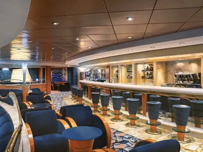 Ein Blick in die schicke Blu Velvet Bar an Bord der MSC Musica mit einer langen Theke, Hockern und blauen Samtsesseln.