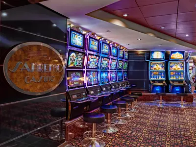 Casino an Bord der MSC Musica. Reihen beleuchteter Spielautomaten mit Hocker. Linke Wand zeigt ein rundes Sanremo Casino Logo. Gemusterter Teppichboden.