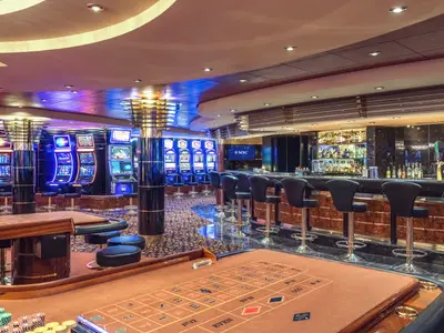 Das Sanremo Casino an Bord der MSC Musica bei Nacht. Es zeigt eine Bar, Reihen von beleuchteten Spielautomaten und einen Roulettetisch im Vordergrund.