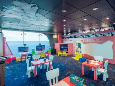 Der farbenfrohe Kinderbereich "Mars School" an Bord der MSC Musica bietet Spieltische, Videospiele, und eine grosse Fensterfront mit Meerblick. Die Decke zeigt ein Raumschiff-Motiv.