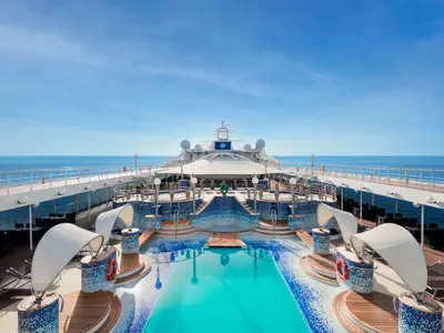 Der Poolbereich 'La Spiaggia' an Bord der MSC Musica mit einem großen türkisfarbenen Pool, Whirlpools und Liegen auf dem Deck. Im Hintergrund das offene Meer unter blauem Himmel.