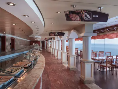 Ein helles Buffetrestaurant an Bord der MSC Musica mit einer langen Serviertheke voller Speisen und vielen Tischen mit Meerblick.
