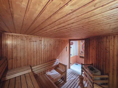 Geräumige Holzsauna im MSC Aurea Spa an Bord der MSC Musica. Die Wände und Decke sind mit hellen Holzpaneelen verkleidet, Holzbänke bieten Sitzgelegenheiten. Eine Tür führt zu einem gefliesten Bereich.