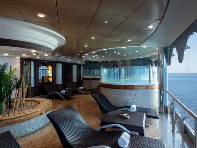 Spa- und Ruhebereich an Bord der MSC Musica. Mehrere Whirlpools, bequeme Liegen und Pflanzen sind zu sehen. Große Fenster bieten Meerblick. Warme Beleuchtung schafft eine entspannte Atmosphäre.