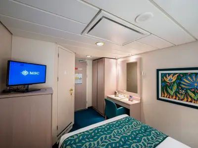Komfortable Aussenkabine an Bord der MSC Opera. Mit Bett, TV, Schreibtisch und Kleiderschrank. Ein farbenfrohes Blumenbild ziert die Wand über dem Bett.